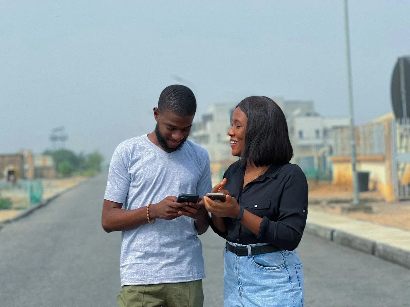 Two friends on a street in Lagos smiling at a phone screen